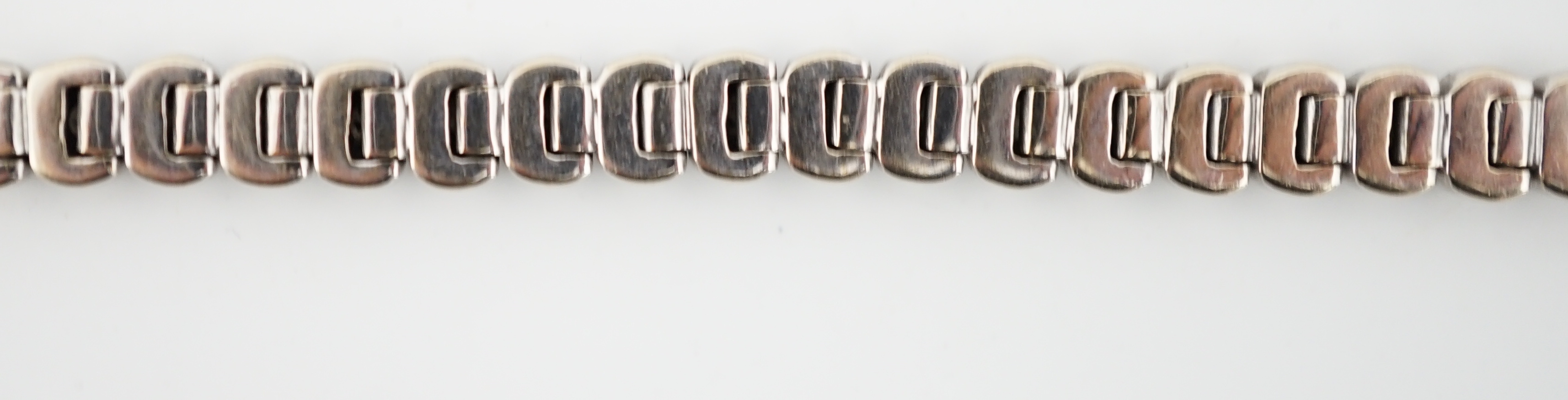 A modern 18ct white gold and collet set forty seven stone round brilliant cut diamond set line bracelet